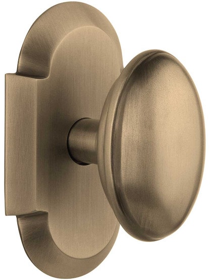 Arched Rosette Door Set with Homestead Knobs in Antique Brass.